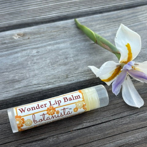 Botanista Wonder Lip Balm tube with orchid flower on wood surface